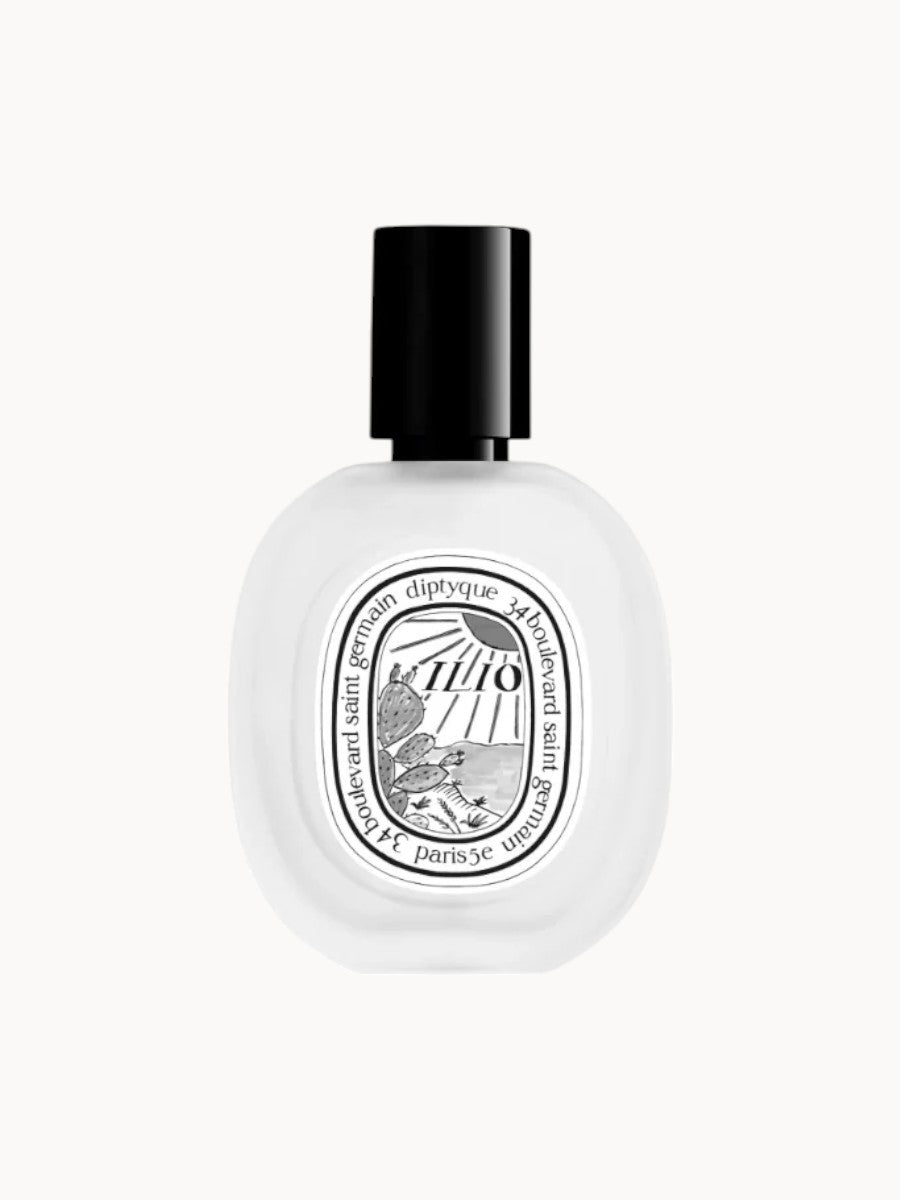 Flakon des Haardufts Diptyque Ilio mit schwarzem Verschluss und ovalem Etikett, darauf ein gezeichneter Sonnenuntergang mit Kaktusmotiv und Produktname.